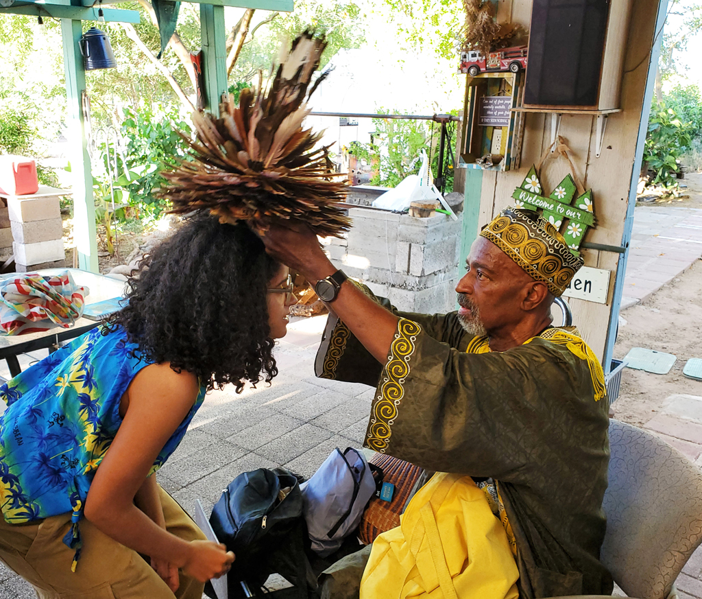 Keith Johnson, CAC board member and specialist in African and Carribean arts, adorns a participant with a feathered head piece.